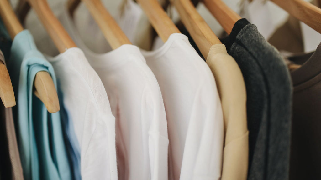 Clothing hanging on coathangers in a wardrobe.